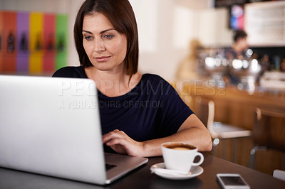 Buy stock photo An attractive woman working on a laptop at a coffee shop
