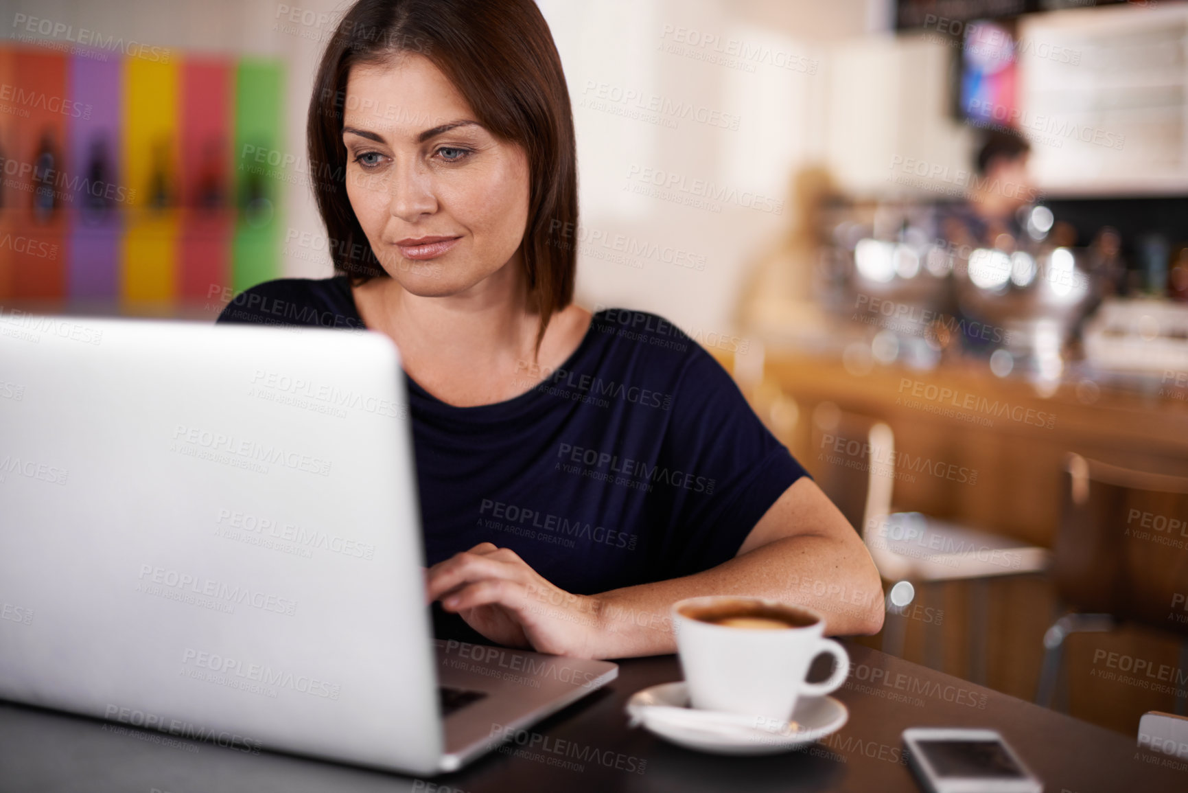 Buy stock photo An attractive woman working on a laptop at a coffee shop