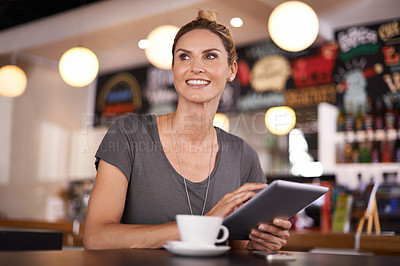 Buy stock photo A beautiful young woman using her tablet at a coffee shop