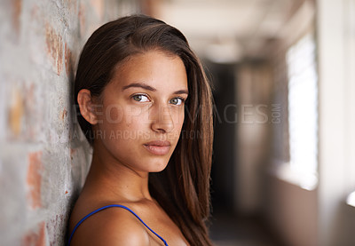 Buy stock photo Portrait, serious and woman by brick for confidence or casual fashion in corridor alone. Face, skin or young student on wall, girl or hair of female person in hallway for profile picture in Argentina