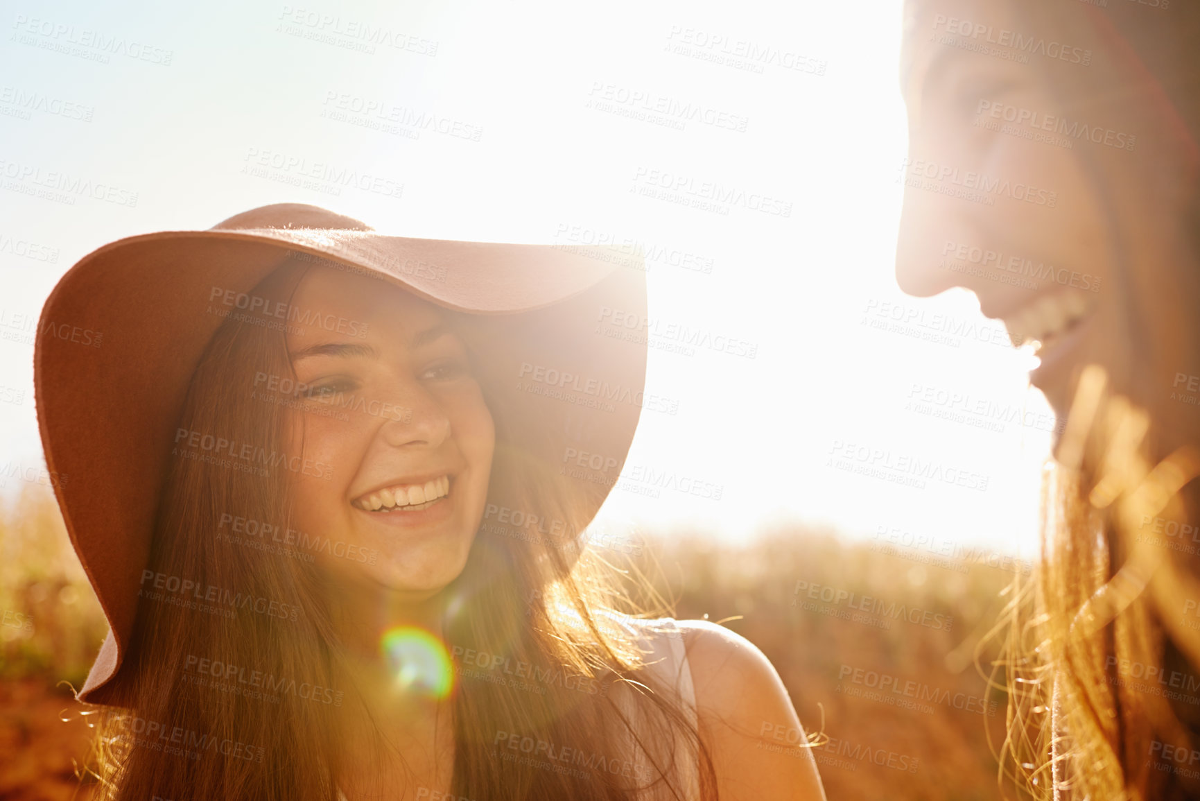 Buy stock photo Women, friends and nature with summer hat for travel, holiday and vacation together in lens flare. Happy and young people in countryside for fashion, talking and laughing with outdoor and cool style