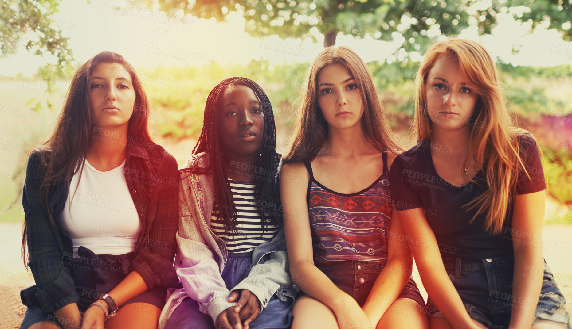 Buy stock photo A group of displeased looking teenage girls sitting outdoors