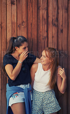 Buy stock photo Two young friends standing outdoors sharing secrets