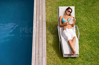 Buy stock photo Woman, pool and relax on chair with book or novel for tanning on holiday or resort in summer and sunshine. Young person in bikini with towel and grass for swimming on vacation in outdoor with story