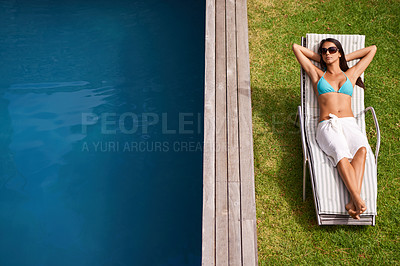 Buy stock photo A beautiful young woman relaxing in a lounge chair by a swimming pool