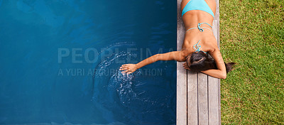 Buy stock photo Shot of a beautiful young woman relaxing by a swimming pool