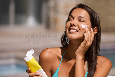 Buy stock photo A beautiful young woman applying suntan lotion to her face