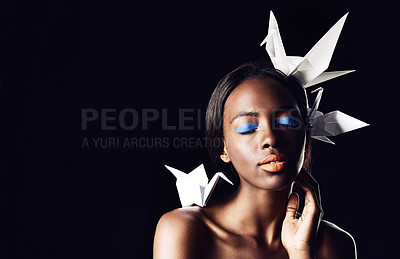 Buy stock photo Black woman, makeup and fine art with beauty, origami birds or cosmetics on a dark studio background. Closeup or face of African female person or model with dove or blue eye shadow on mockup space