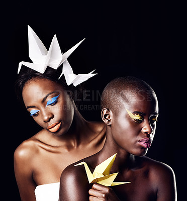 Buy stock photo Cropped shot of two beautiful ethnic women posing with origami against a black background