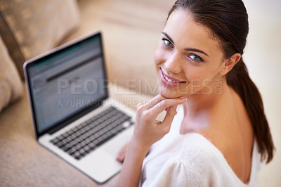 Buy stock photo Shot of a young woman sitting in her living room using a laptop