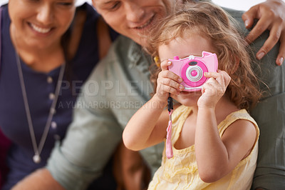 Buy stock photo A little girl playing with a camera as she sits with her parents