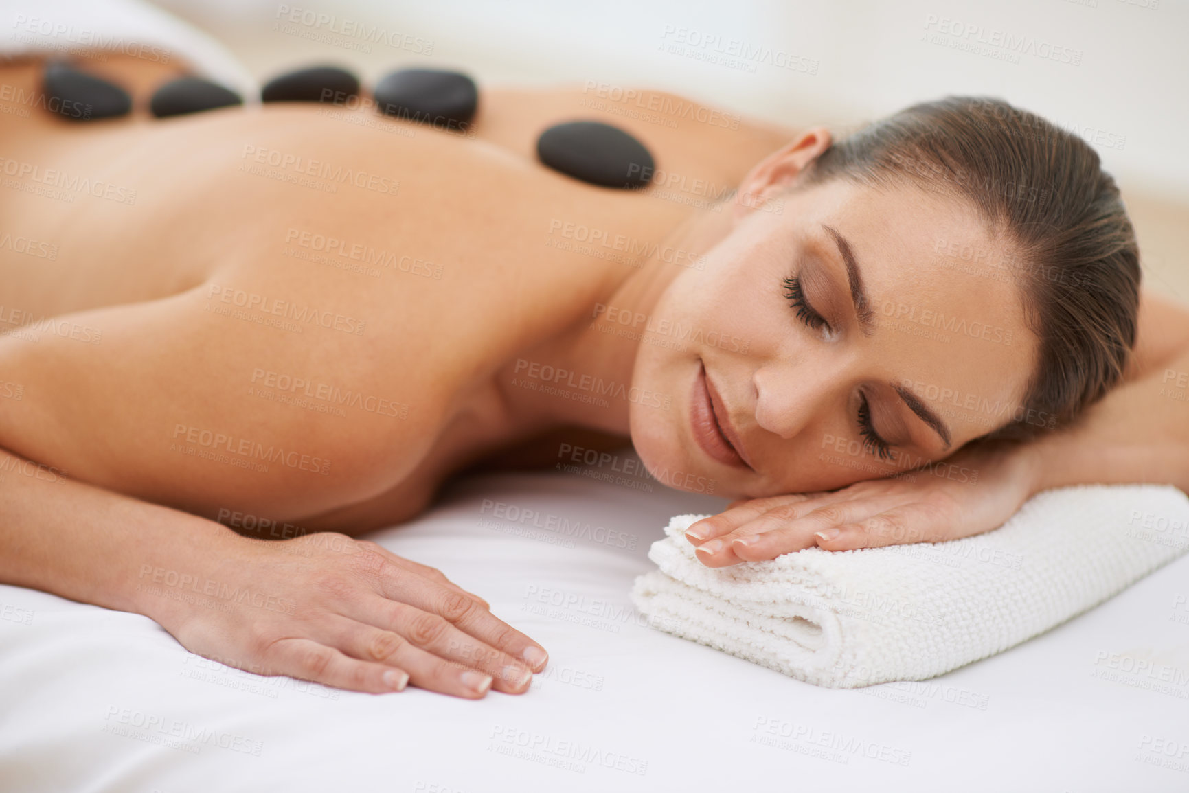 Buy stock photo Relax, hot stone massage and woman on bed at spa for health, zen wellness and luxury holistic treatment. Self care, peace and girl on table for body therapy, comfort and calm pamper service at hotel
