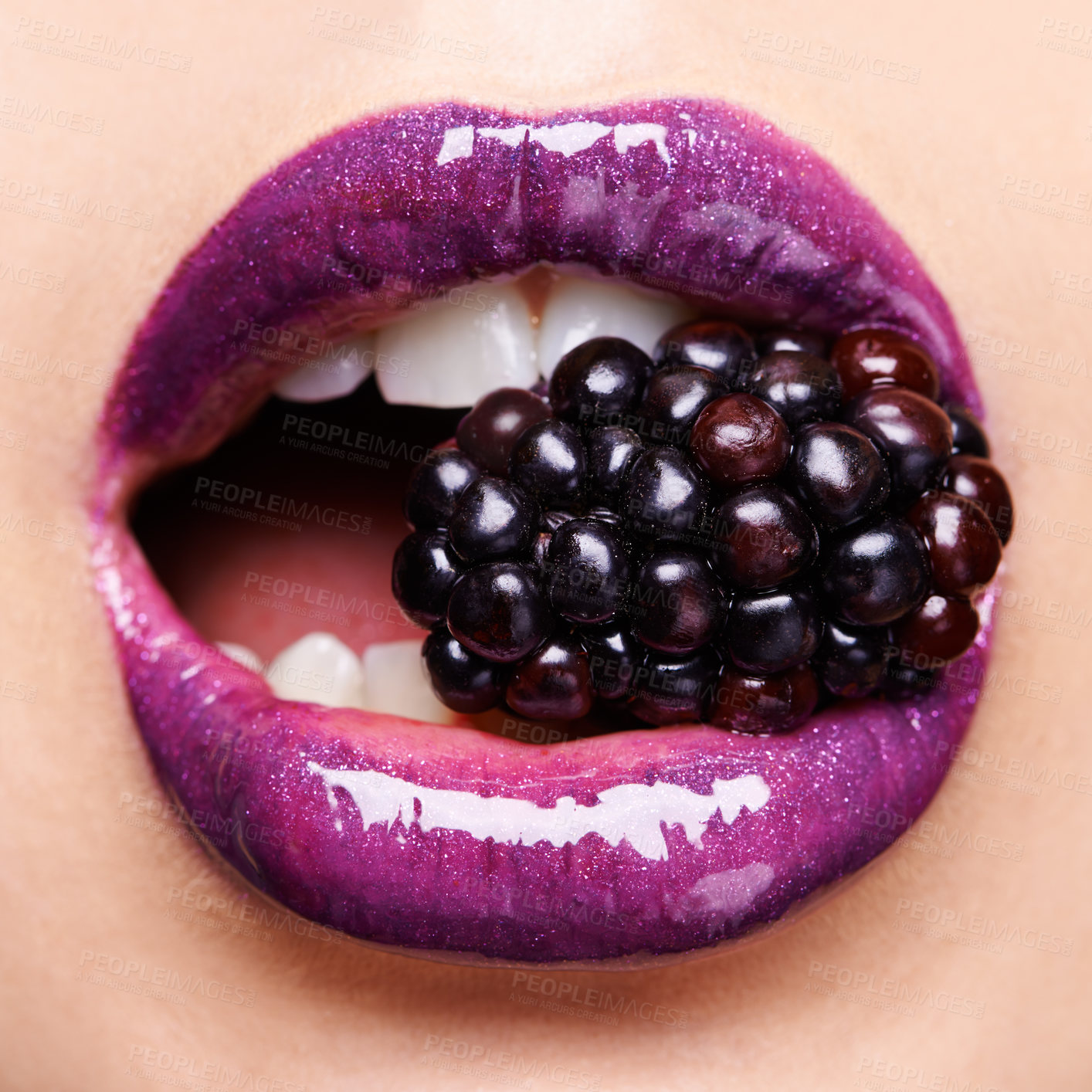 Buy stock photo Shot of a woman wearing purple lipstick and biting into a blackberry