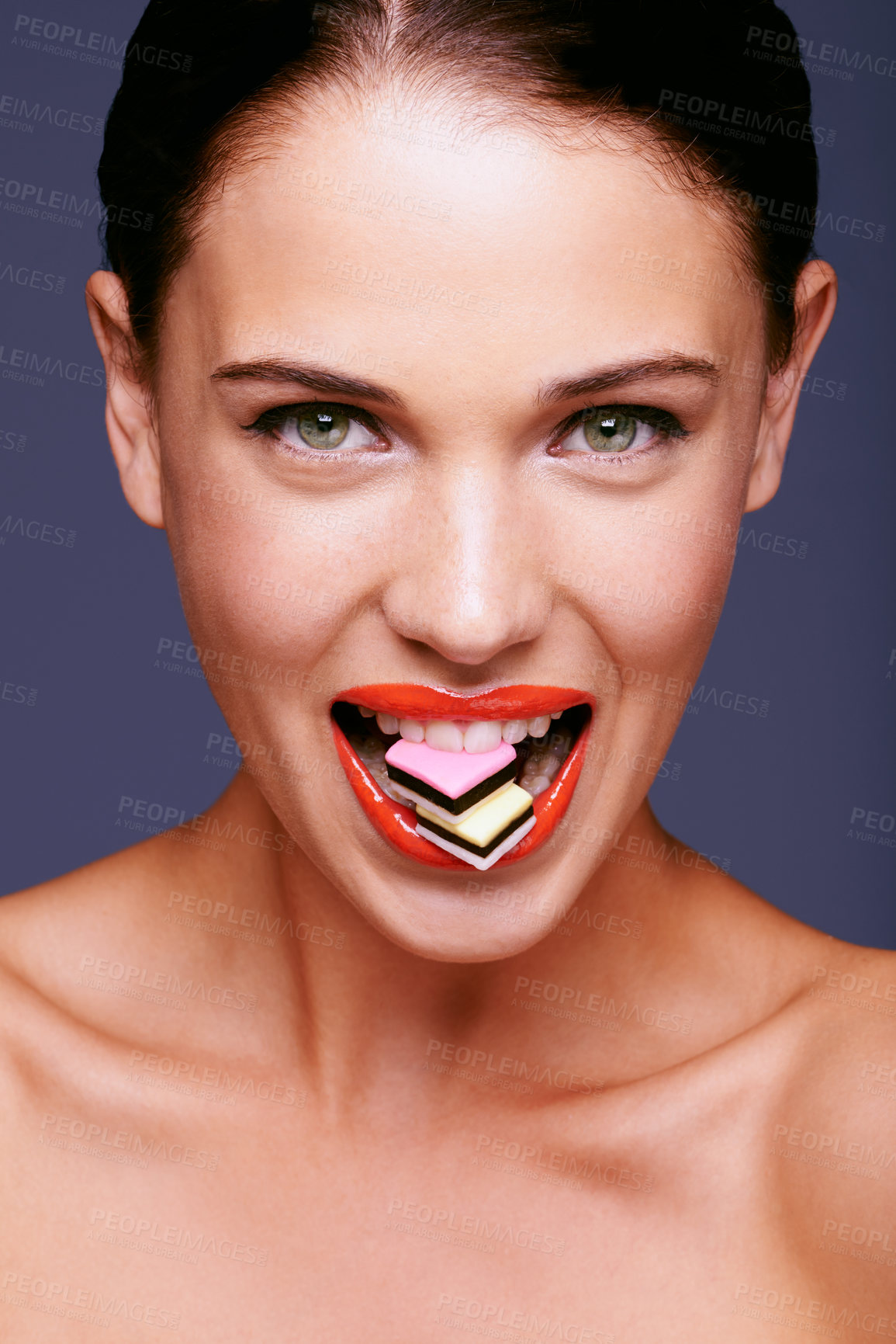 Buy stock photo Beauty, lipstick and woman in portrait with candy in mouth, makeup and creativity with shiny cosmetic product. Licorice, sweets and orange lip gloss for aesthetic with art on purple background