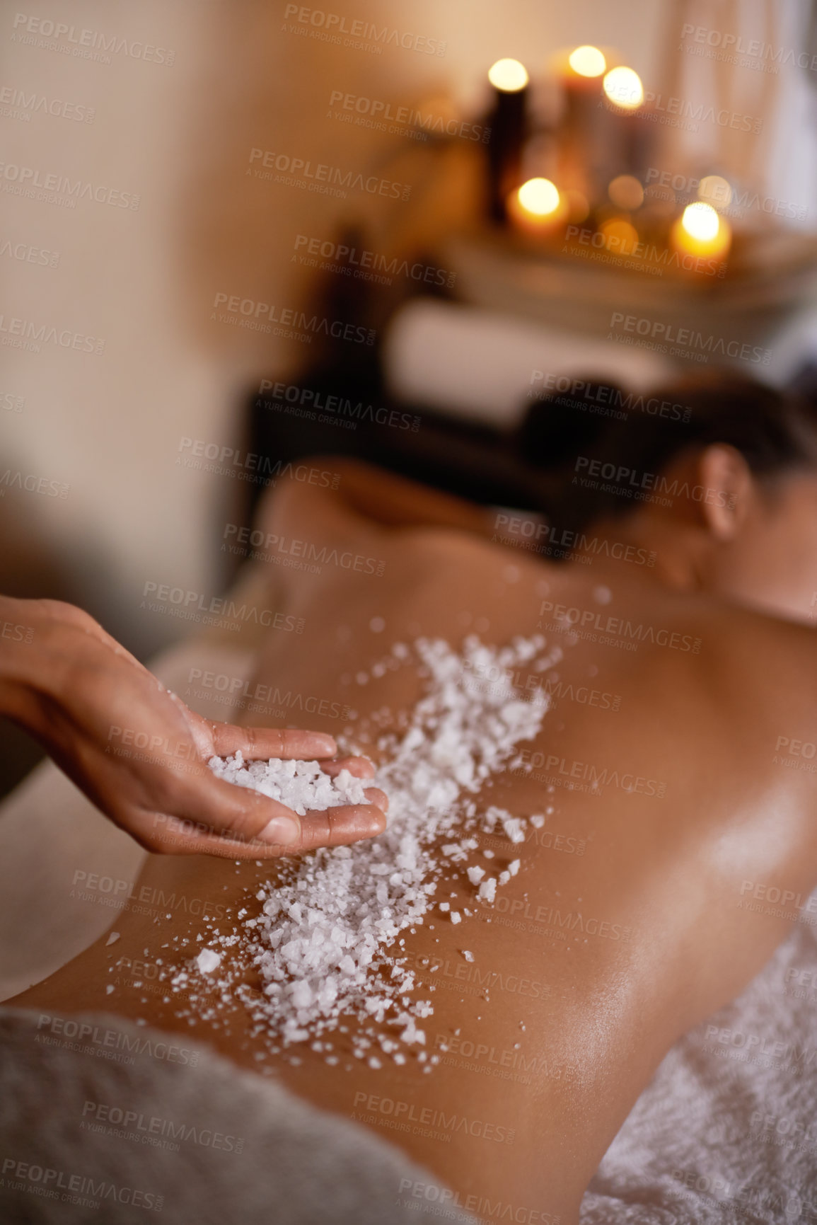 Buy stock photo Shot of a young woman enjoying a salt exfoliation treatment at a spa