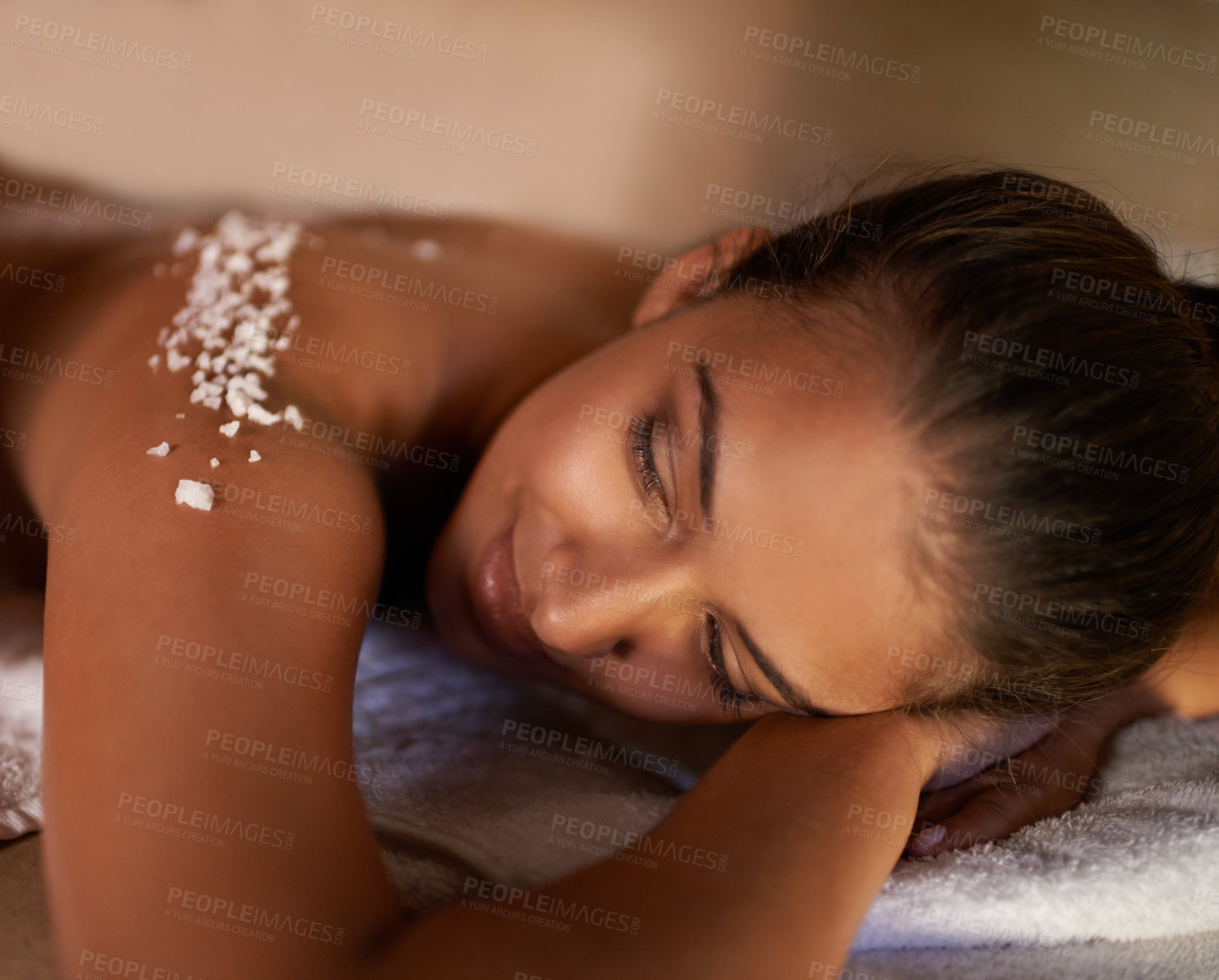 Buy stock photo Face, massage and salt with woman at spa on bed or table for luxury pamper treatment or exfoliation. Beauty, peace or skincare and young customer at resort or salon to relax with holistic wellness