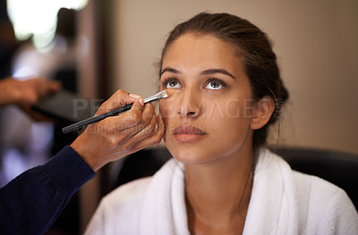 Buy stock photo Shot of an attractive young woman having makeup applied to her face