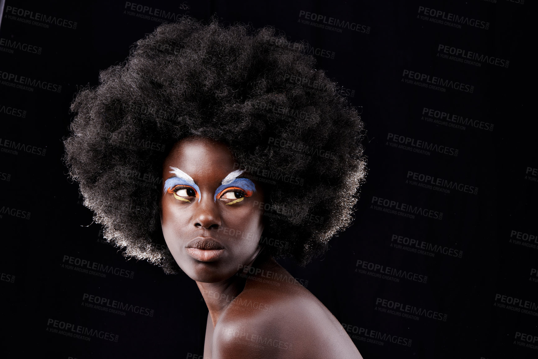 Buy stock photo Studio shot of a beautiful young model wearing colorful eye makeup posing against a black background