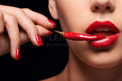 Buy stock photo Closeup of a woman holding a red chilli to her mouth