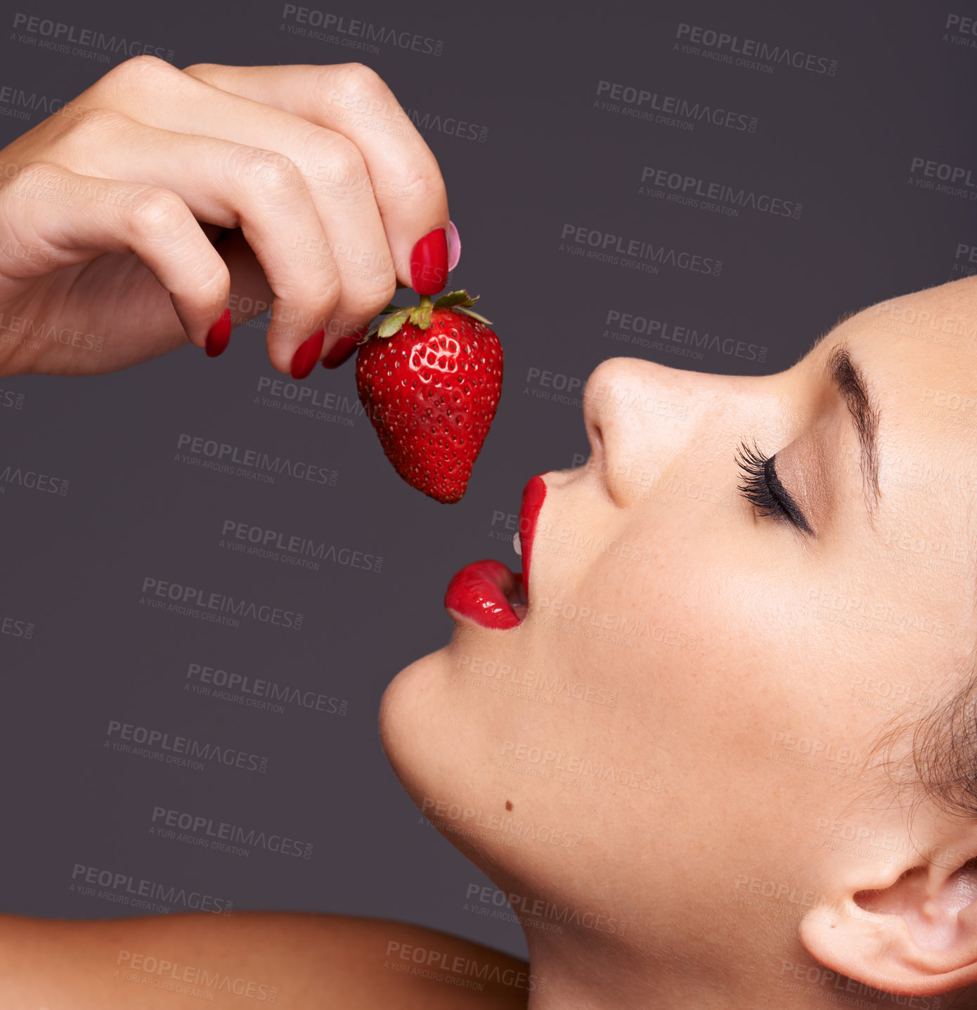 Buy stock photo Closeup portrait of a beautiful young woman with strawberry in her mouth