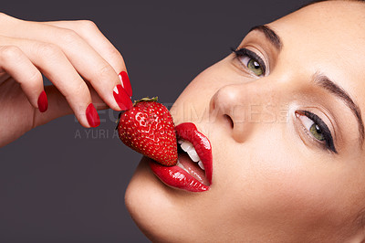 Buy stock photo Makeup, portrait and woman with a strawberry in a studio with red nails and lipstick cosmetics. Health, wellness and closeup of a female model eating fruit for nutrition isolated by a gray background