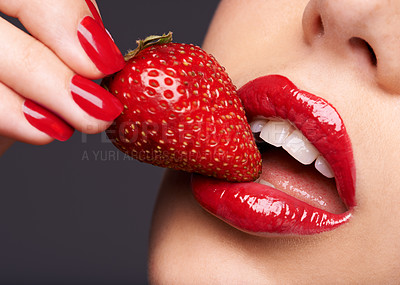 Buy stock photo Beauty, makeup and woman with a strawberry in a studio with red nails and lipstick cosmetics. Health, wellness and closeup of a female model eating fruit for nutrition isolated by a gray background.