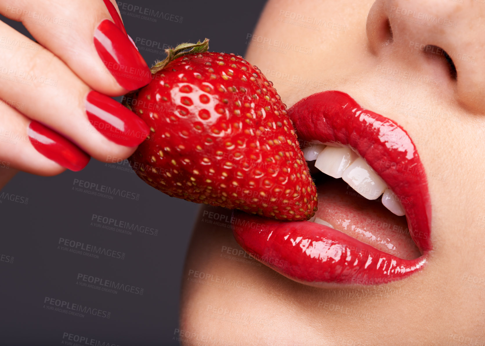 Buy stock photo Beauty, makeup and woman with a strawberry in a studio with red nails and lipstick cosmetics. Health, wellness and closeup of a female model eating fruit for nutrition isolated by a gray background.