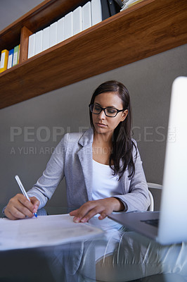 Buy stock photo Shot of an attractive young businesswoman working on some paperwork at her desk