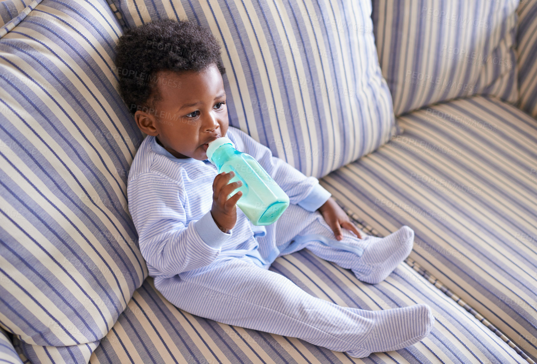 Buy stock photo Baby, bottle or sofa for nutrition, health or growth by morning breakfast meal in living room. Hungry, black boy or mouth on couch to drink, milk or formula for early childhood progress or care