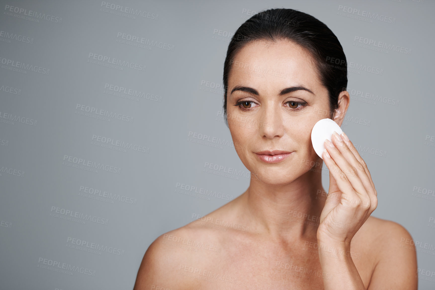 Buy stock photo Mature woman, pad and cleanse in studio, skin care and facial treatment on gray background. Female person, cotton and swab for grooming in daily routine, mockup space and dermatology to remove makeup