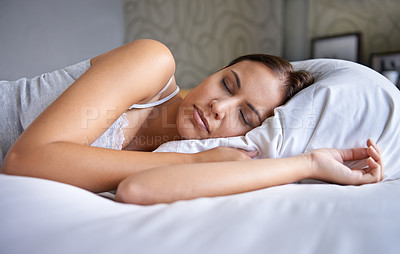 Buy stock photo Cropped shot of a young woman lying on a bed