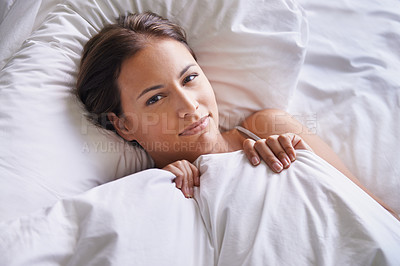 Buy stock photo Cropped shot of a young woman lying on a bed