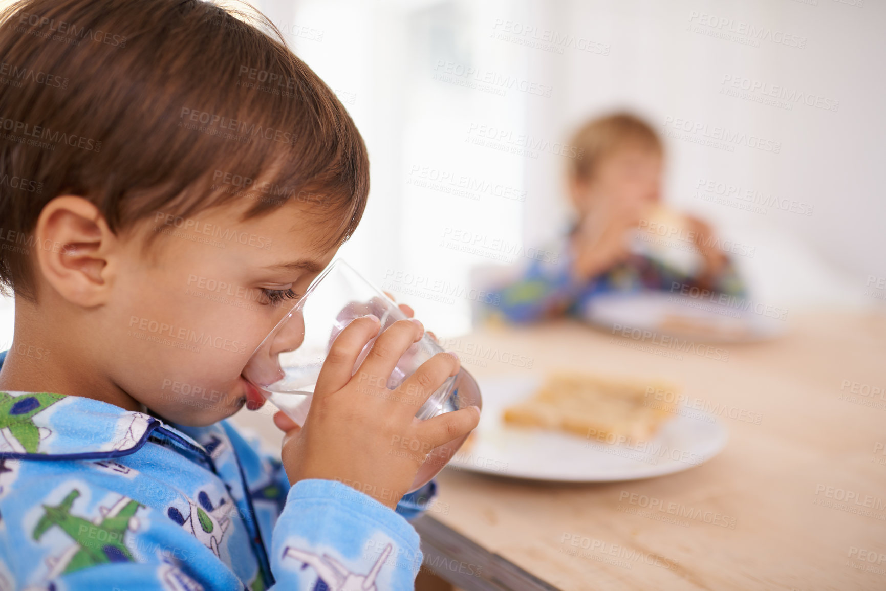 Buy stock photo A cute little boy having a drink of water with breakfast