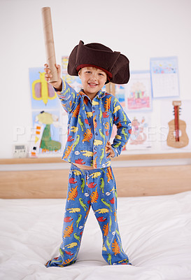 Buy stock photo Child, portrait and happy for pirate game, character and creativity in bedroom or at home. An excited boy or kid on a bed with cardboard, cap and pajamas for fun holiday, imagination and play alone