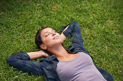 Buy stock photo High angle shot of an attractive young woman lying on the grass