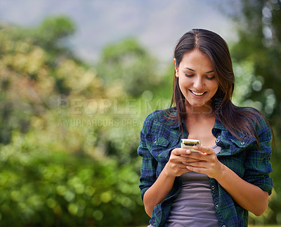 Buy stock photo Shot of an attractive young woman using her cellphone outside in a garden