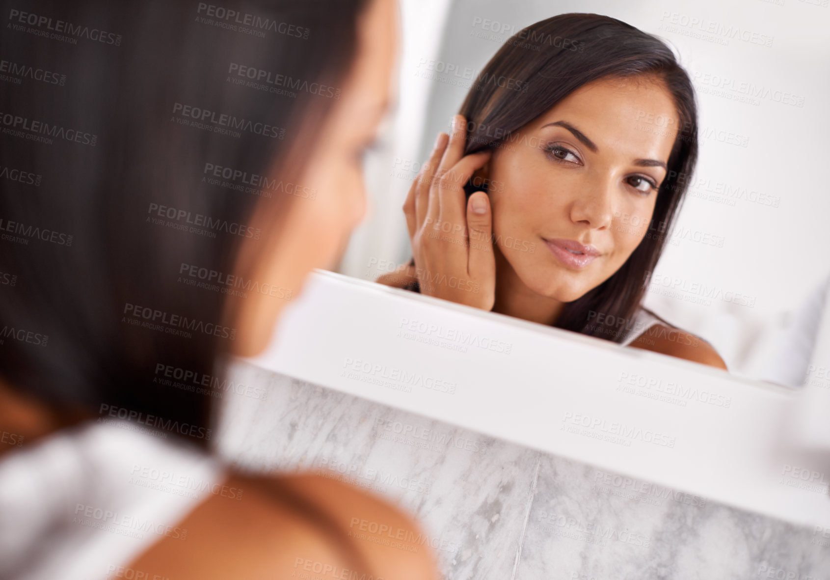 Buy stock photo Shot of a beautiful young woman looking at her face in the mirror