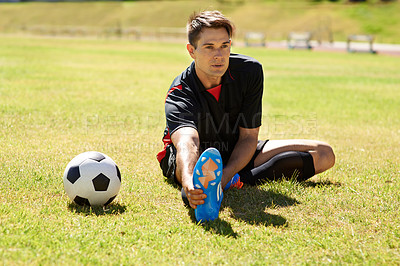 Buy stock photo Shot of a young footballer stretching on the field