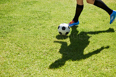 Buy stock photo Shot of a young footballer dribbling the ball on a field