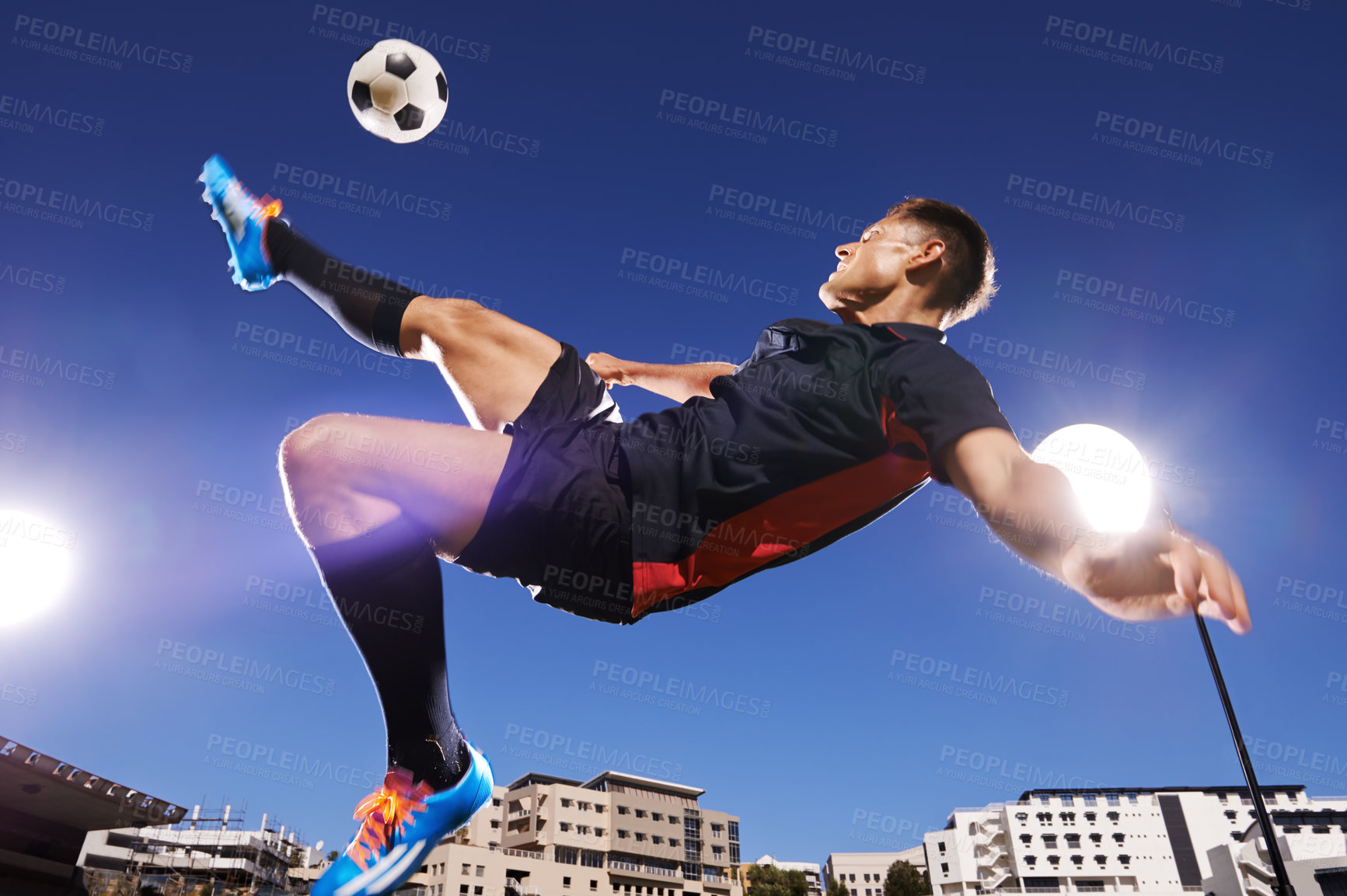 Buy stock photo Shot of a young footballer kicking a ball in mid-air