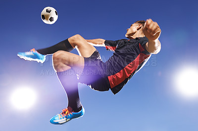 Buy stock photo Shot of a young footballer kicking a ball in mid-air