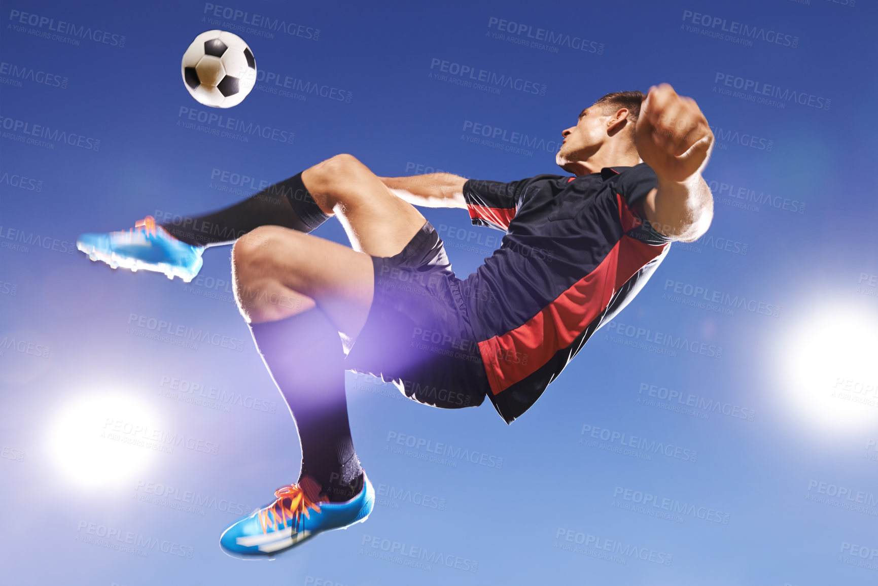 Buy stock photo Shot of a young footballer kicking a ball in mid-air