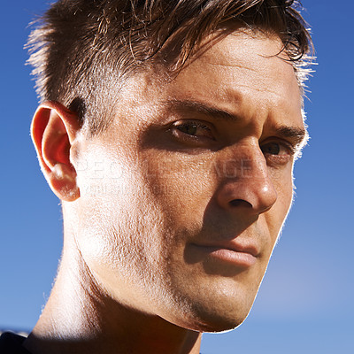 Buy stock photo Man, portrait and confident soccer player in outdoors, athlete and competitive for match or game. Male person, serious face and determined for competition, blue sky and focus for football challenge