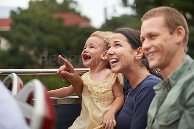 Buy stock photo Shot of a young family sitting on a bus while the mother points to the sky