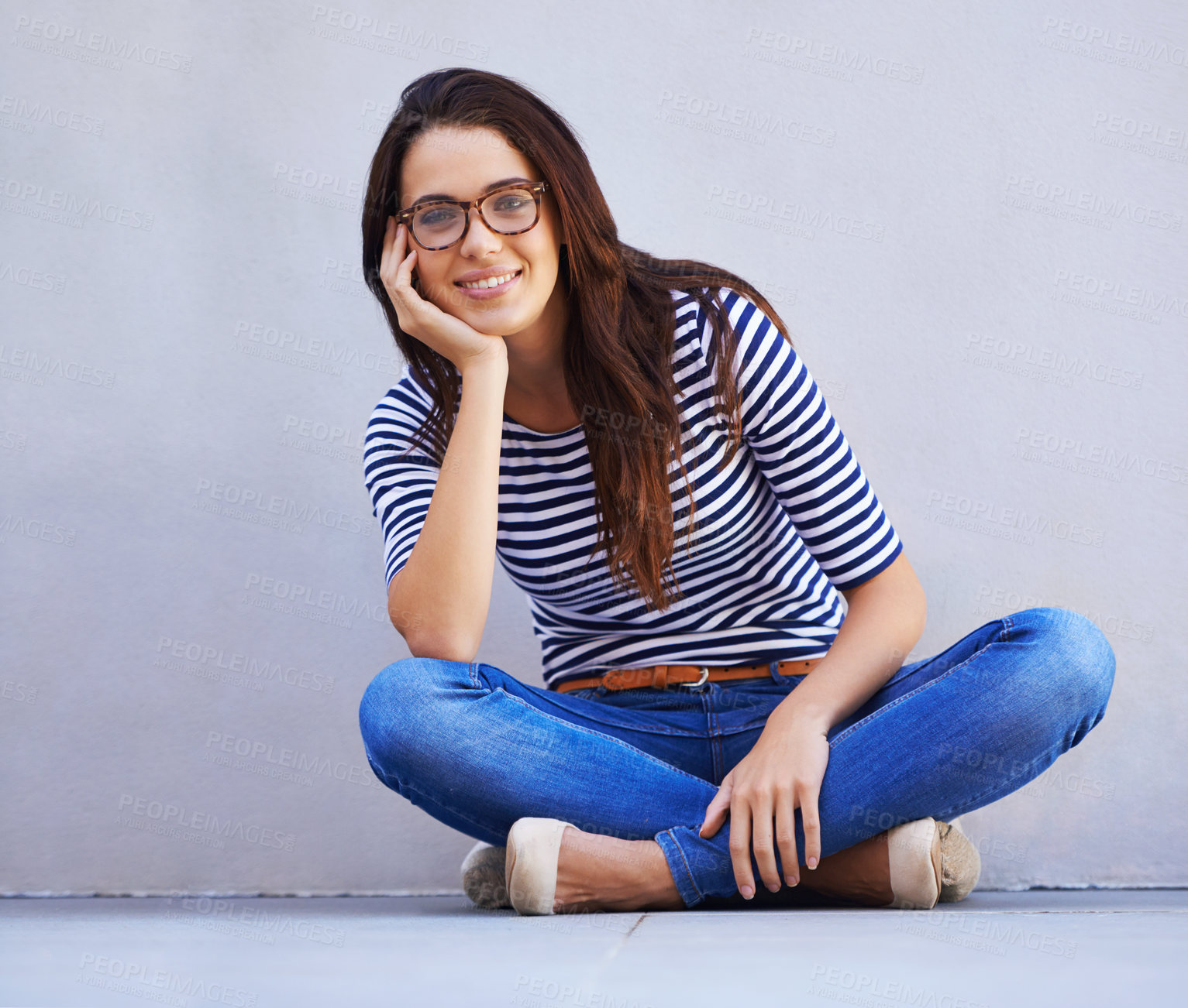 Buy stock photo Happy, fashion and portrait of woman on floor with wall background for casual or trendy style. Smile, model and relax with confident young person legs crossed in glasses for casual clothing outfit