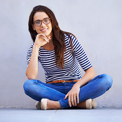 Buy stock photo Portrait, fashion and smile of woman on floor with wall background for casual or trendy style. Happy, model and relax with confident young person legs crossed in glasses for casual clothing outfit