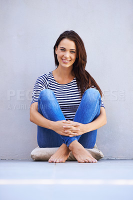 Buy stock photo Full-length portrait of a beautiful young woman hugging her knees while sitting on the floor