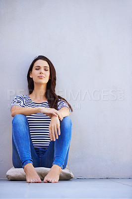 Buy stock photo Full-length shot of a beautiful young woman daydreaming while sitting on the floor