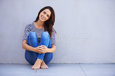 Buy stock photo Full-length portrait of a beautiful young woman hugging her knees while sitting on the floor