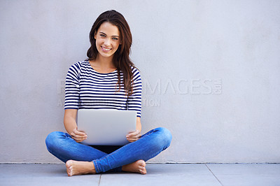 Buy stock photo Full-length shot of an attractive young woman sitting cross-legged using a laptop